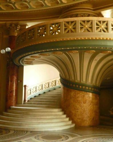 The magnificent foyer includes these marble staircases that sweep up to curved balconies 