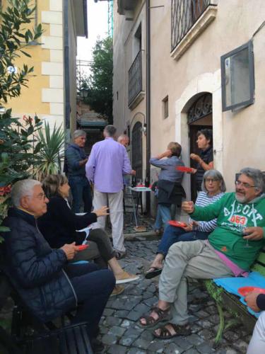 Gatherings like this one are regular events; the houses are small so tables and chairs are set out in the street (propped up with whatever's handy to make them more or less level), friends arrive, food and wine is served and conversation flows