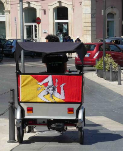 The Sicilian flag is unusual; it's charactertised by a triskelion (a three-legged symbol) representing the triangular shape of the island, the winged head of Medusa and three ears of wheat 