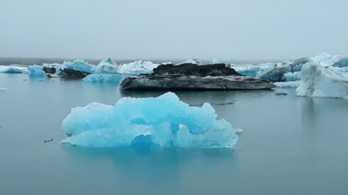 When ice is first exposed to air it's bright blue (this piece would be an iceberg that has recently flipped over); the black ice has come from the bottom of the glacier (where it has ground along collecting volcanic ash and dirt )